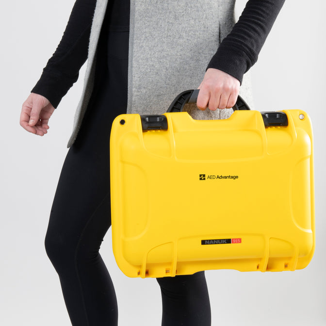 A woman carrying a bright yellow AED hard case.