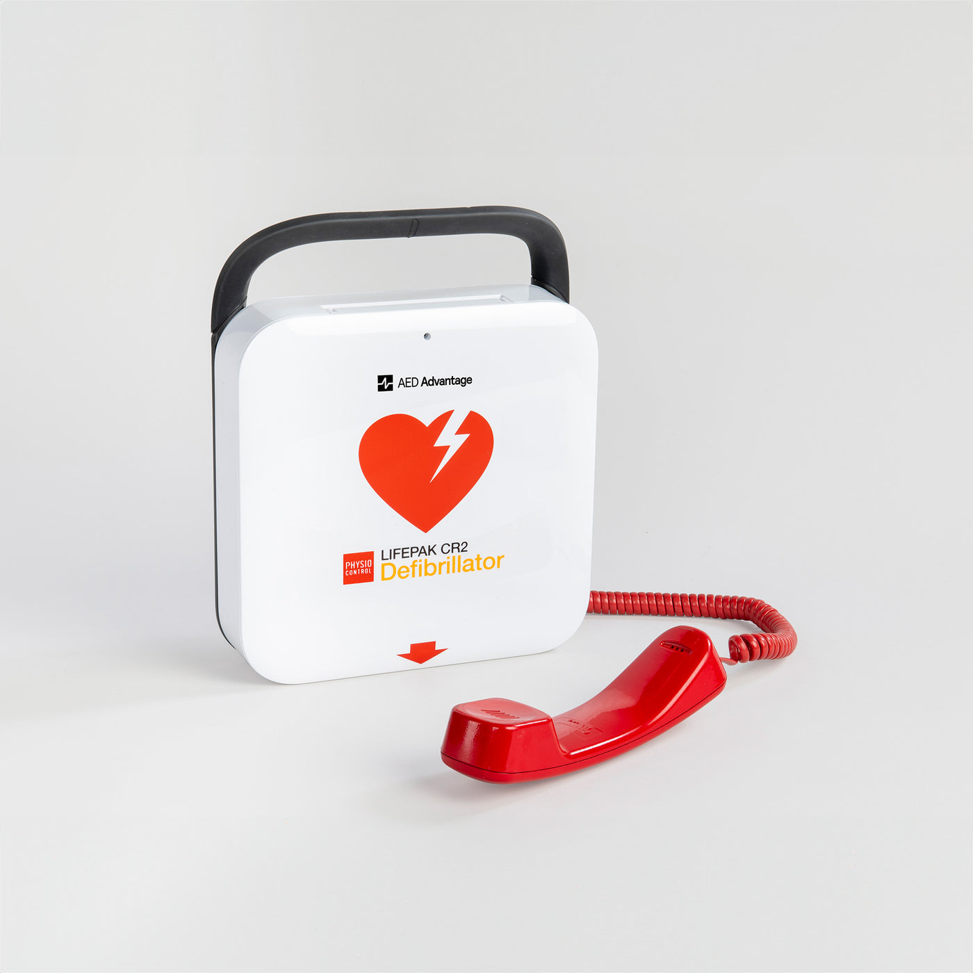 A white and red LIFEPAK AED with a bright red telephone laying in front of it.