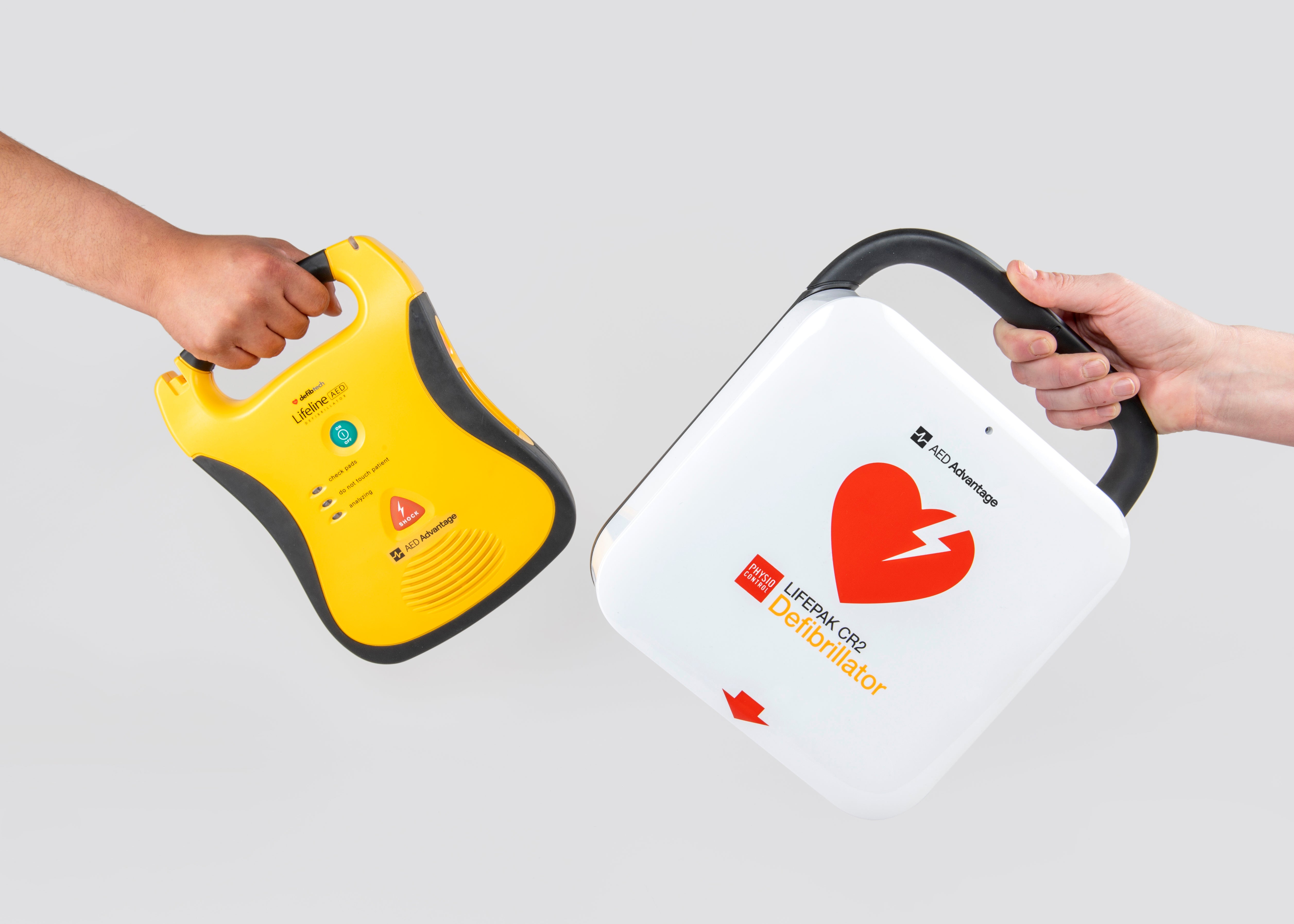 Two hands exchanging AED machines