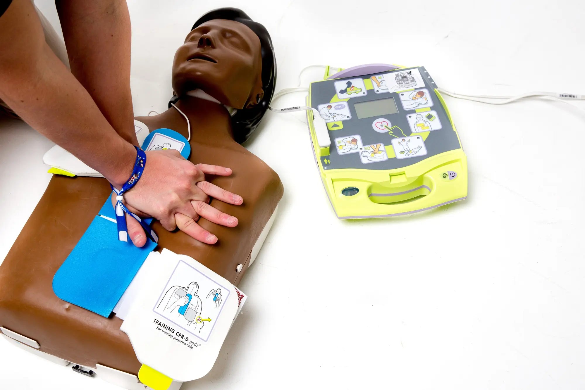 A first responder administering CPR on a CPR dummy that is hooked up to an AED.