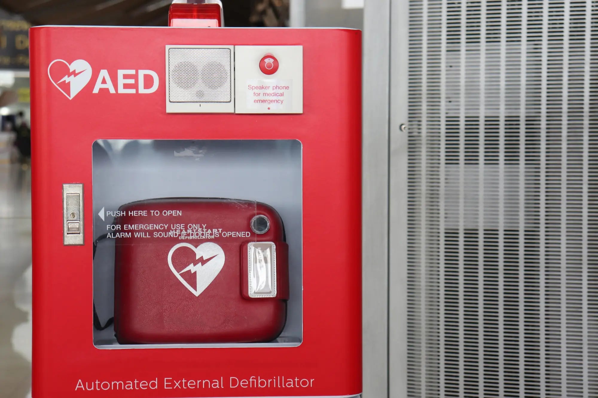 A red Philips OnSite AED in a red outdoor cabinet