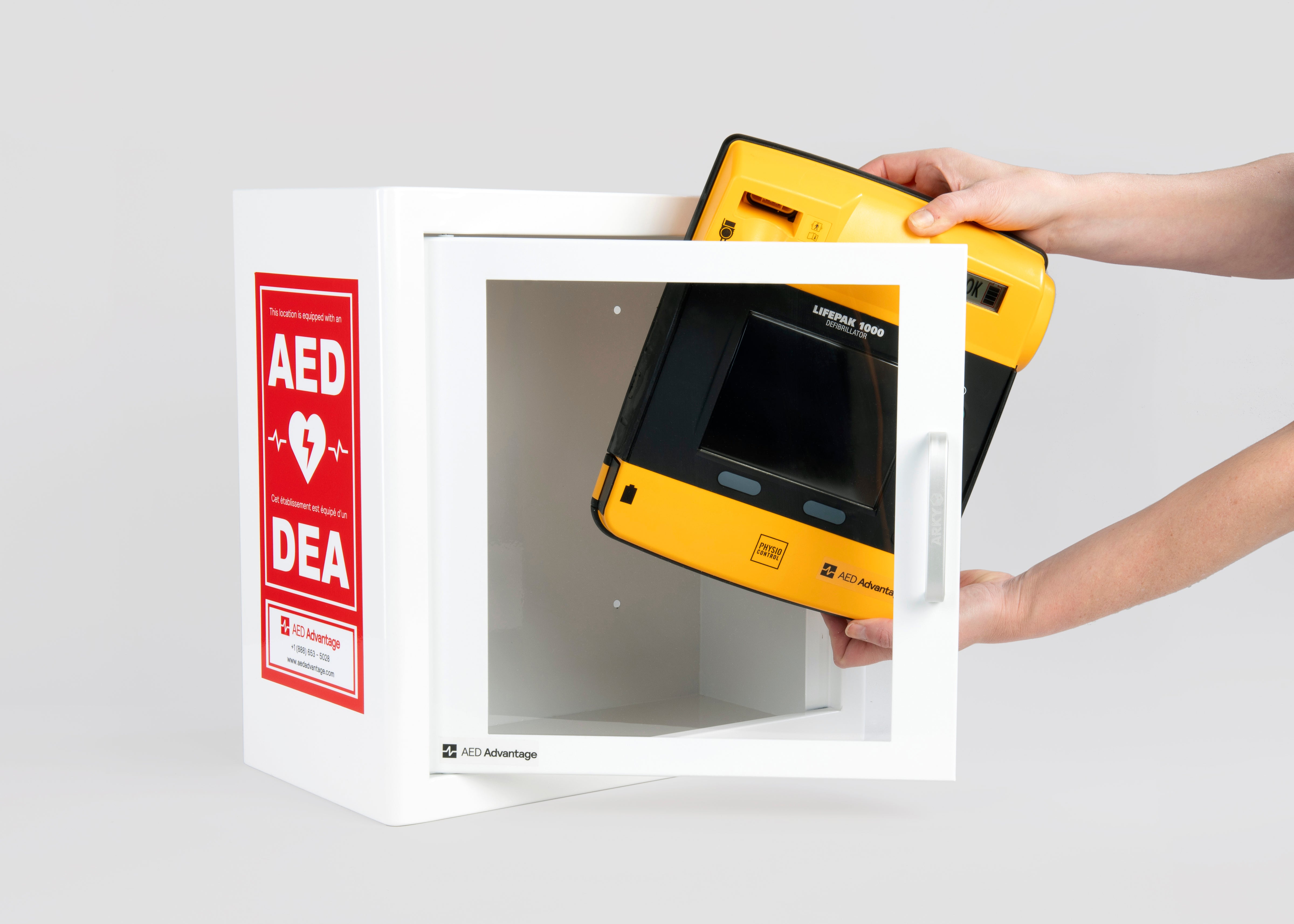 A black and yellow LIFEPAK 1000 AED being retrieved by hand from a white metal cabinet with red decals