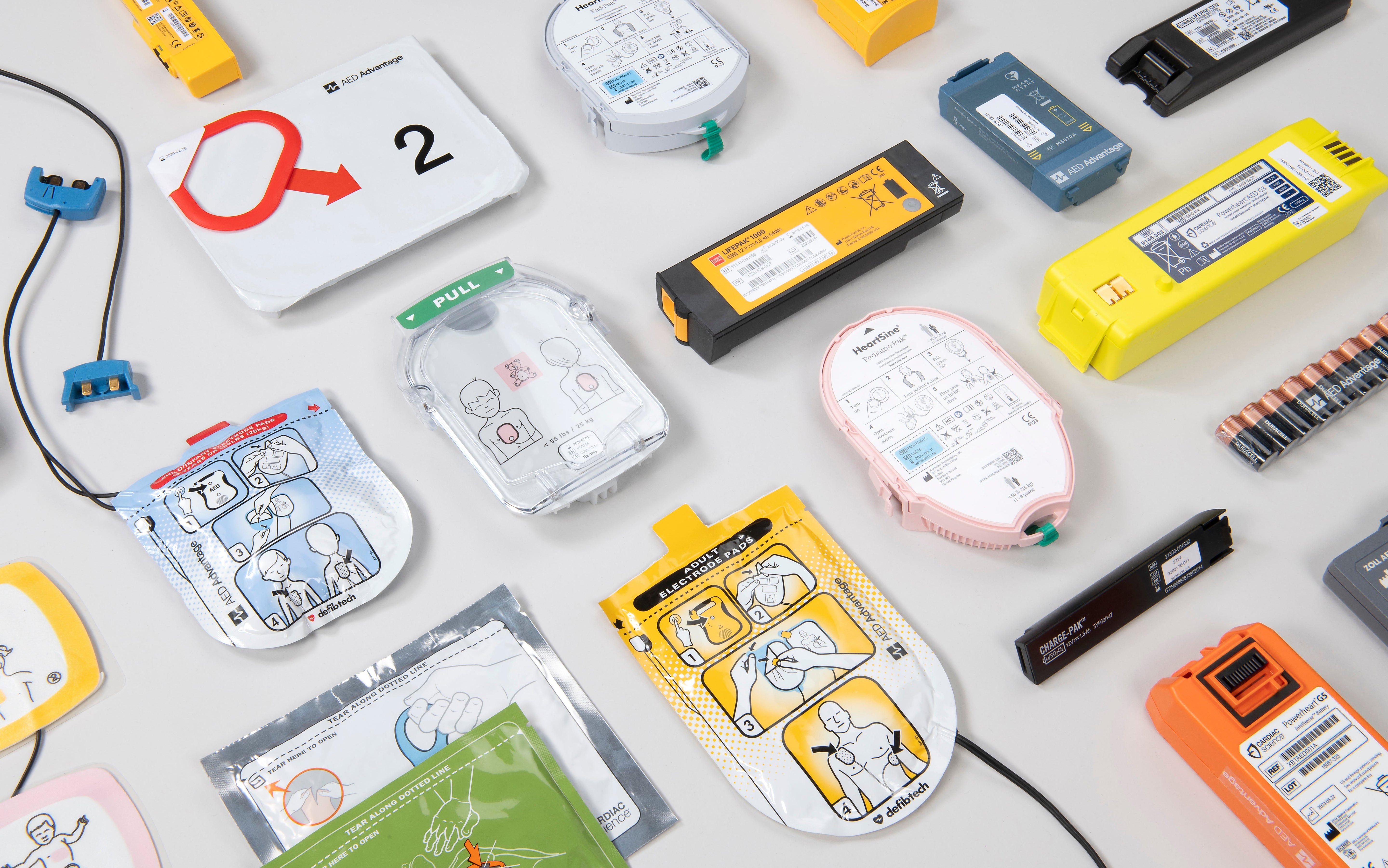 A collage of multi-colored pads and batteries for various defibrillators