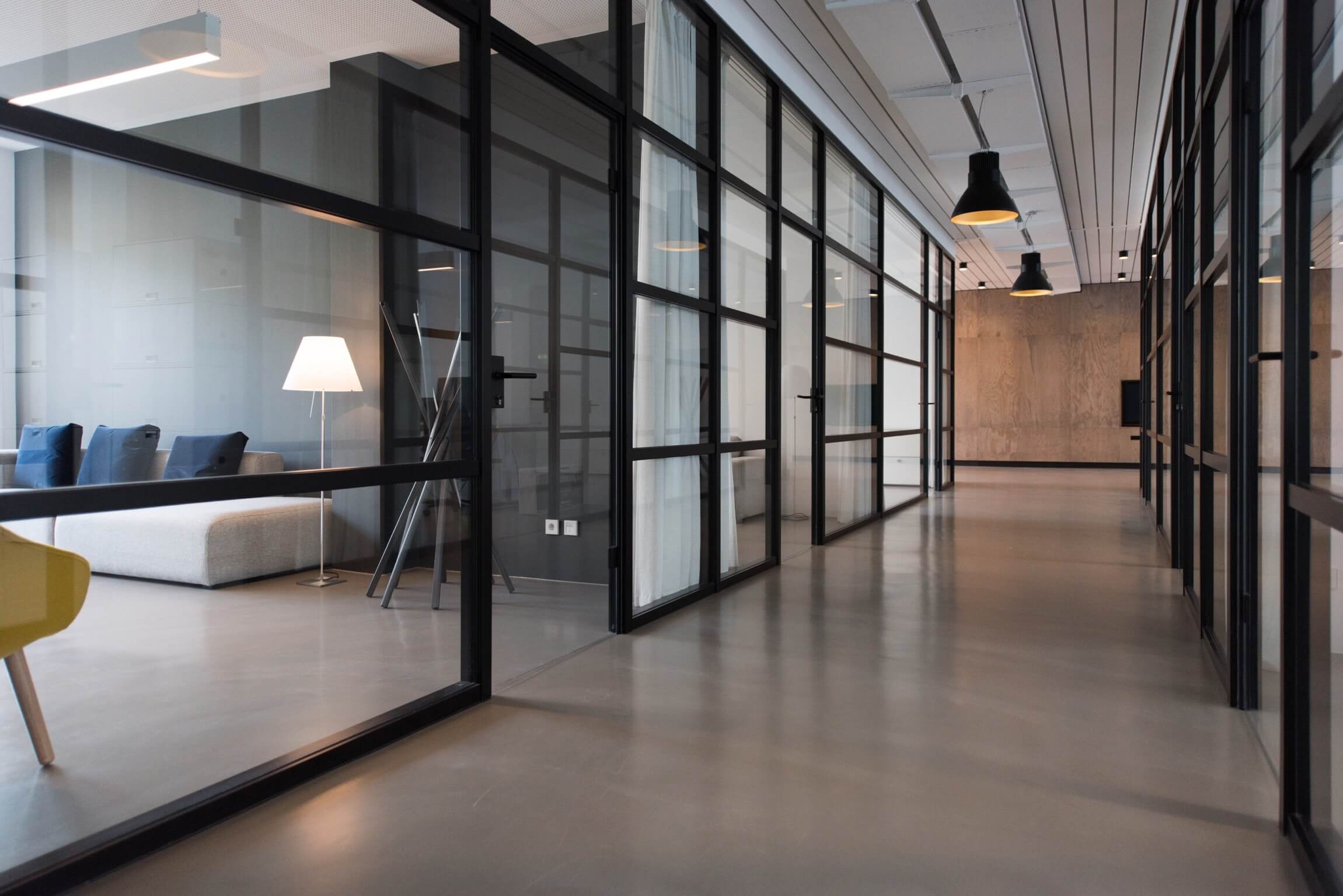 A hallway in a corporate office with glass walls partitioning offices