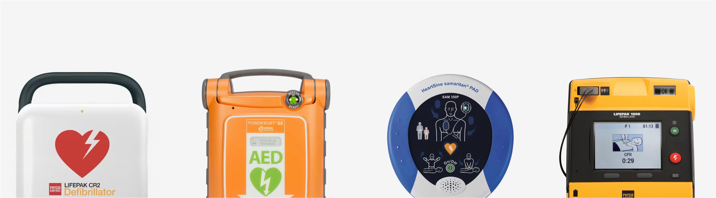 Four AEDs of various colours standing in a line.