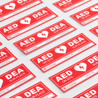 A collage of red rectangular decals that adhere to doors indicating an AED is present at a facility