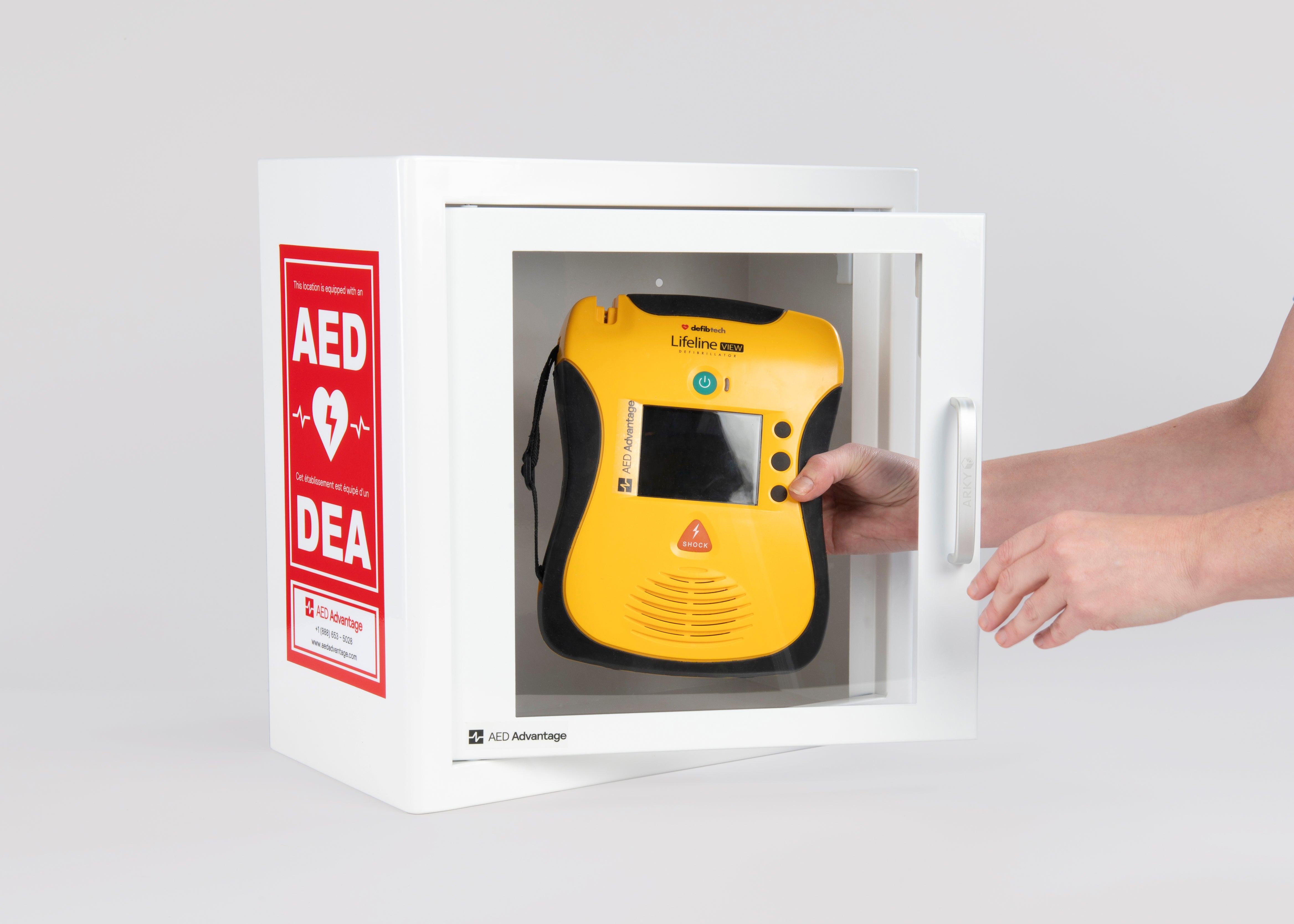 A yellow and black Defibtech Lifeline VIEW AED being retrieved by hand from a white metal cabinet with red decals