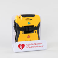 A black and yellow Defibtech Lifeline VIEW AED strapped into a white metal wall mount bracket