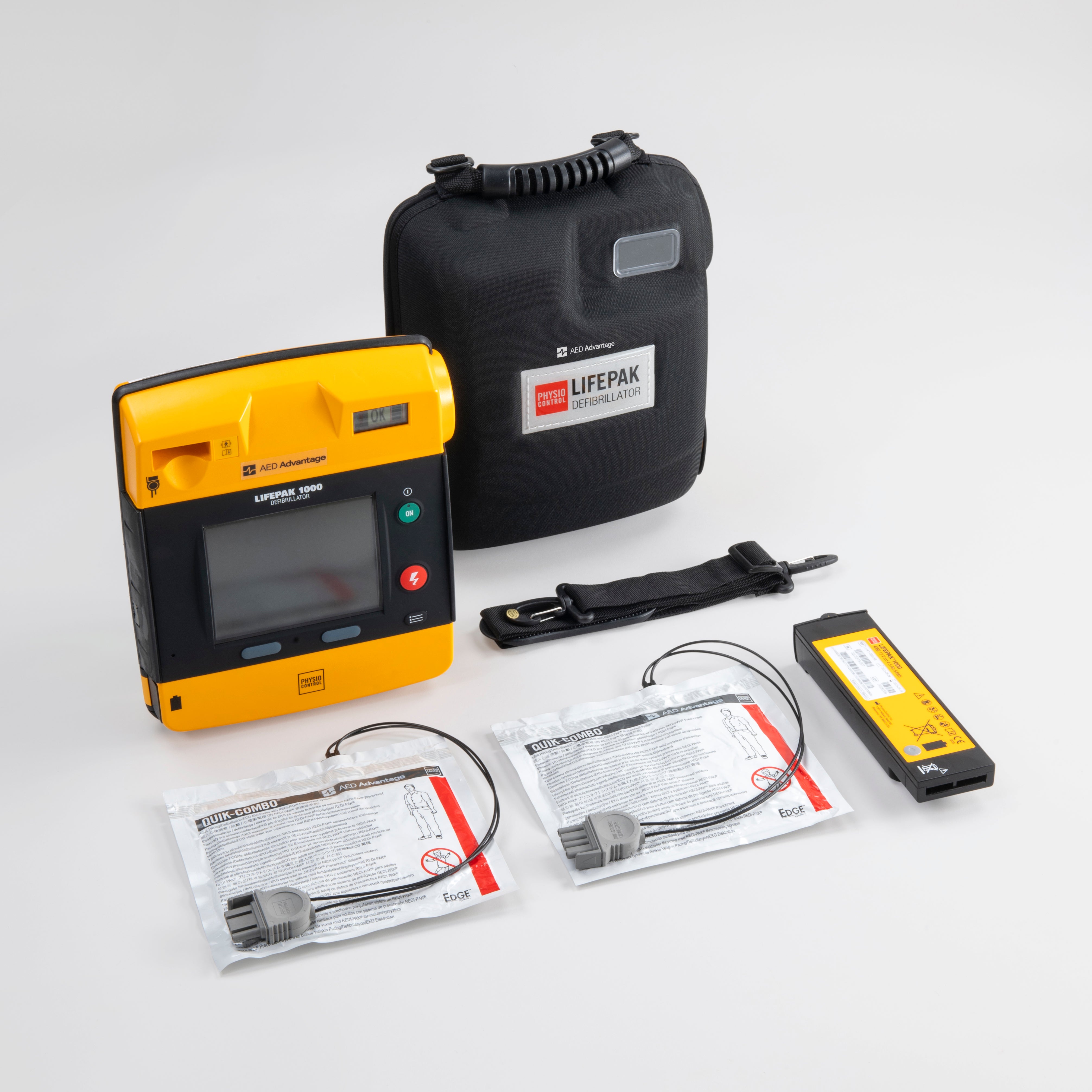 A black and yellow LIFEPAK 1000 AED with its black carry case, two electrode pads, and a battery