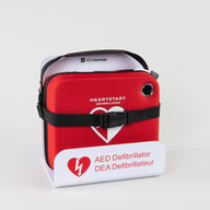 A Philips OnSite AED in a bright red carry case strapped into a white metal wall mount bracket