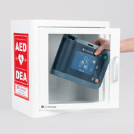 A blue Philips FRx AED being retrieved by hand from a white metal cabinet with red decals