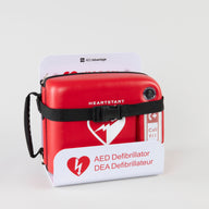 A Philips FRx AED in a bright red carry case strapped into a white metal wall mount bracket