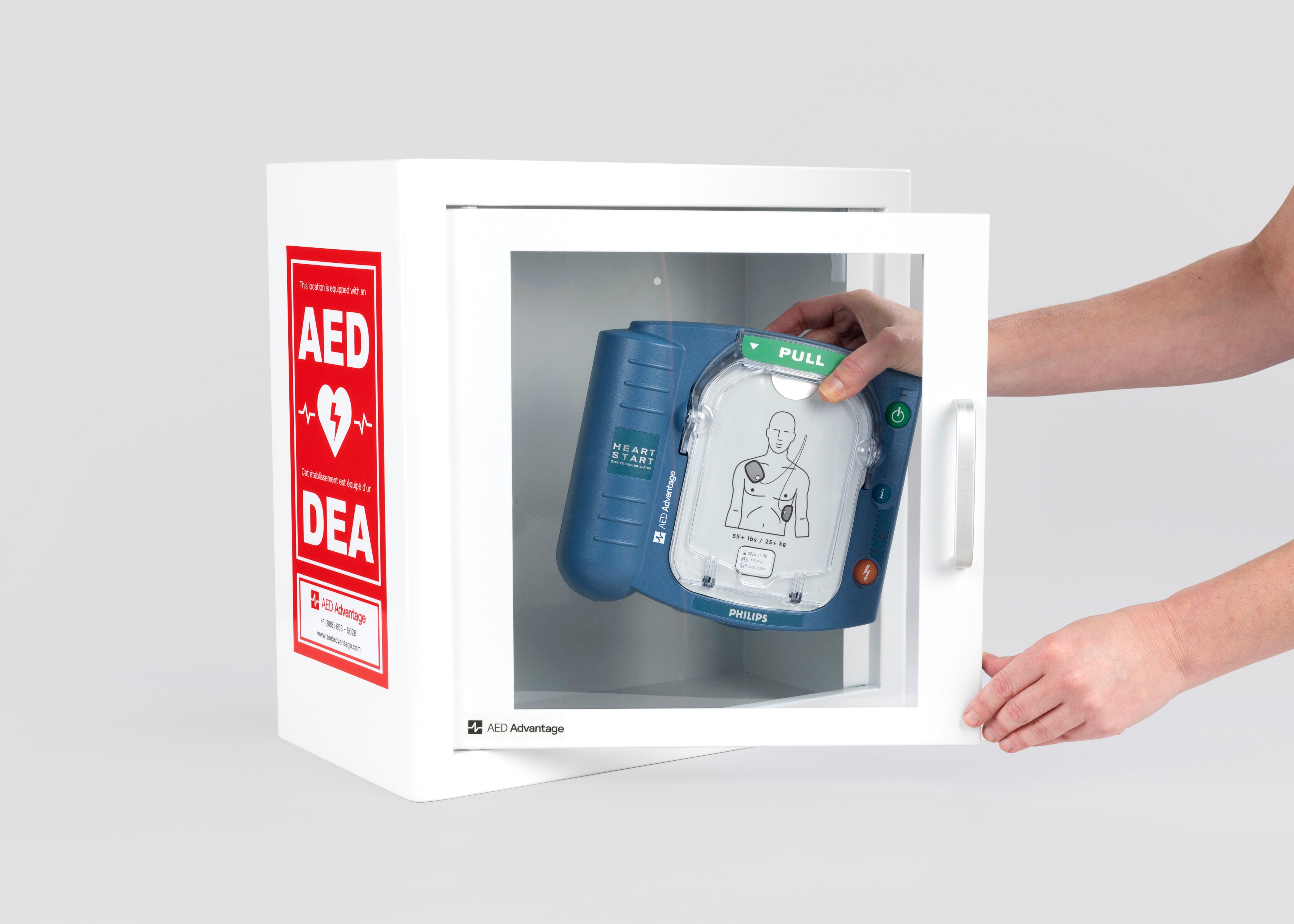 A blue Philips OnSite AED being retrieved by hand from a white metal cabinet with red decals