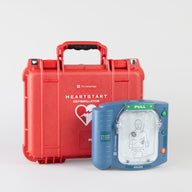 A blue Philips OnSite AED standing next to a bright red hardshell carry case