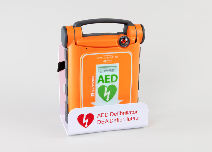 An orange Powerheart G5 AED displayed in a white metal wall mount bracket