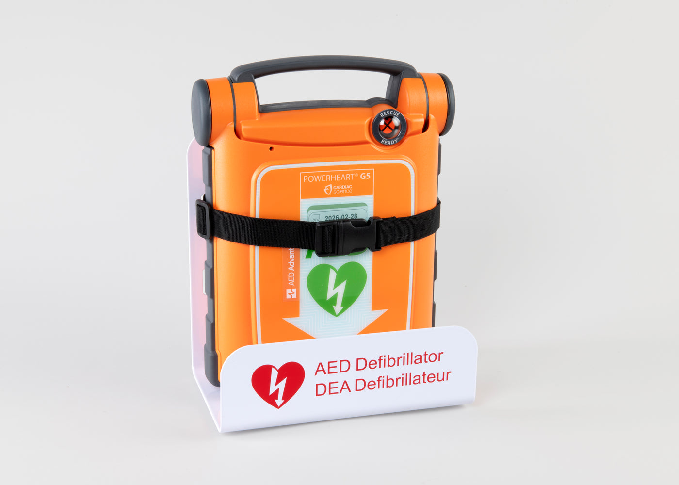An orange Powerheart G5 AED strapped into a white metal wall mount bracket