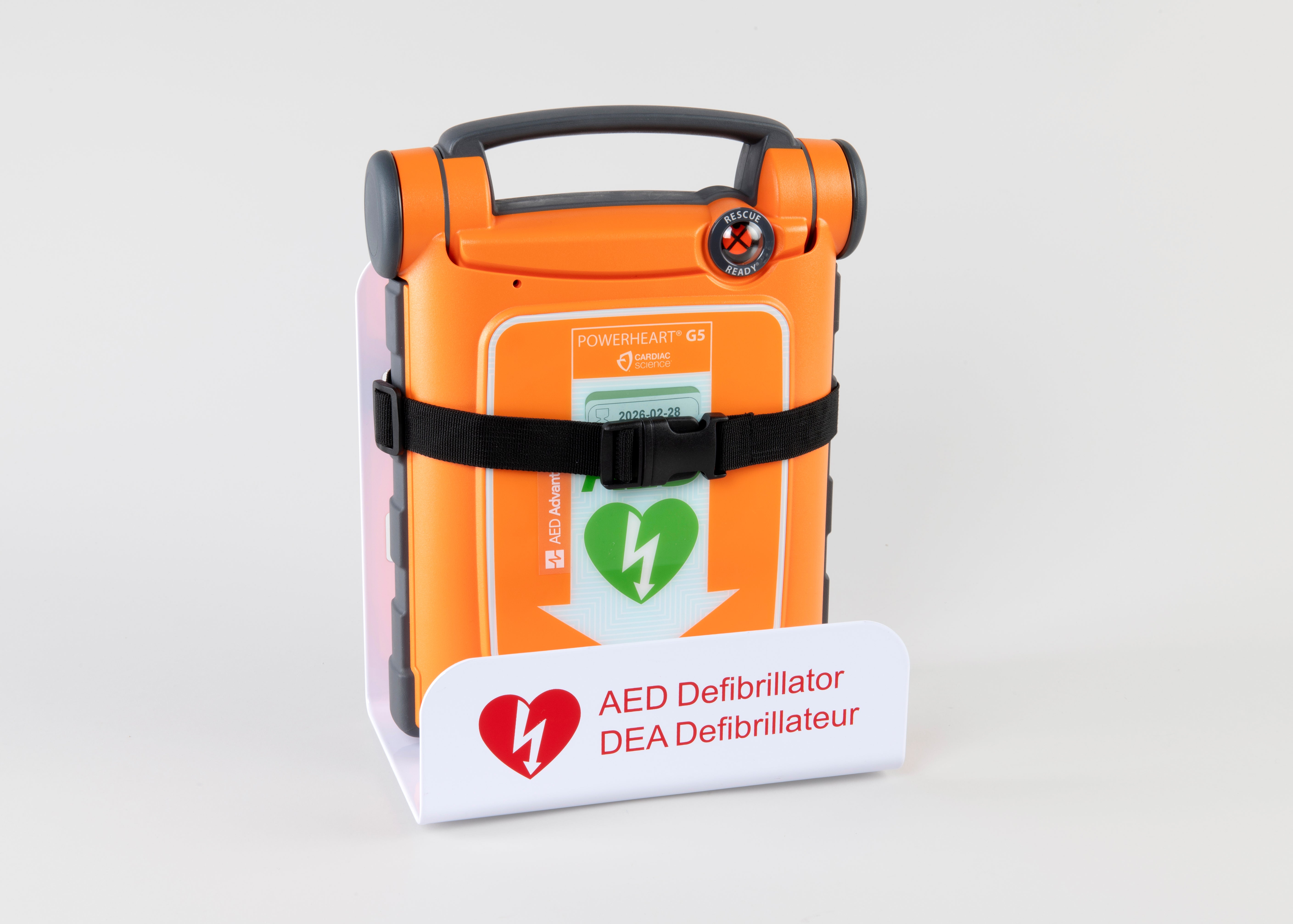 An orange Powerheart G5 AED strapped into a white metal wall mount bracket