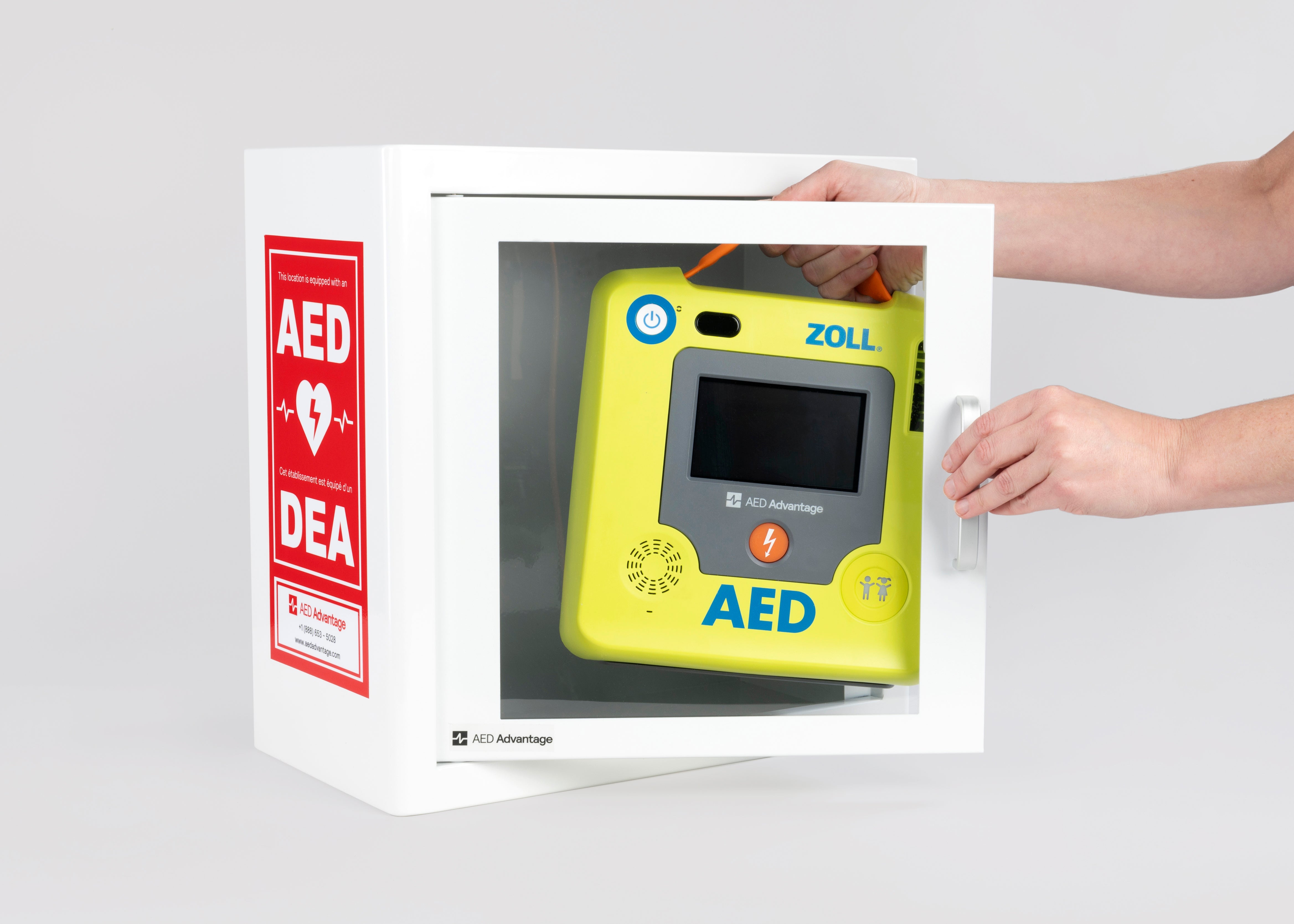A green ZOLL AED 3 machine being retrieved by hand from a white metal cabinet with red decals