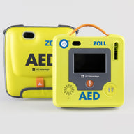 A green ZOLL AED 3 machine standing next to its green semi-rigid carry case